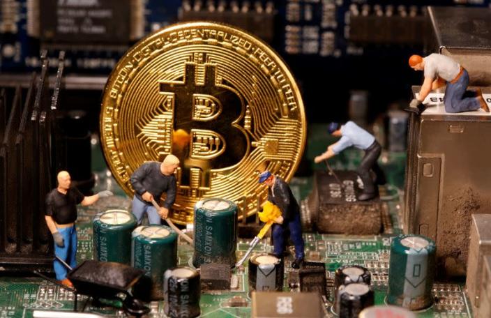 Bitcoin and small toy figures placed on a computer motherboard